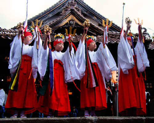 4 young Miko performing miko mai at an small shrines annual festival.