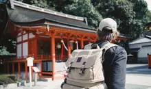 Homme avec son sac à dos devant un temple japonais