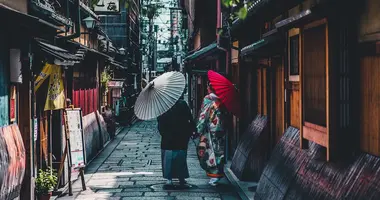 Pareja caminando por la calle sosteniendo paraguas en Kioto