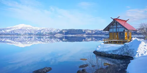 Kansaki Palace stands on Lake Tazawa & the lakeside, & beyond the lake, there’s a distant view of Mt. Akita Komagatake (Semboku City, in Akita Prefecture).